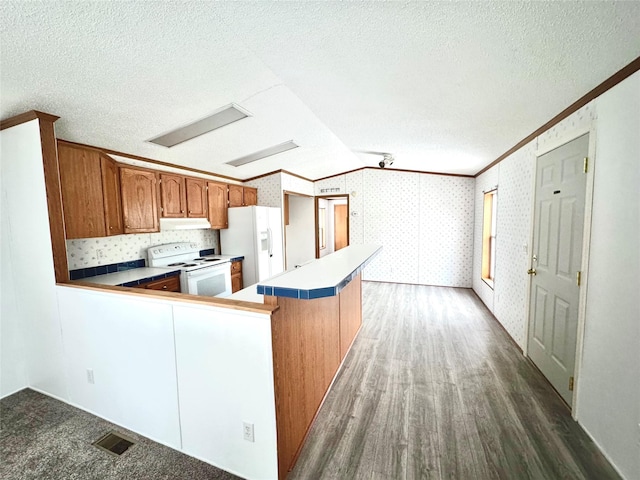 kitchen featuring crown molding, white appliances, dark hardwood / wood-style floors, a textured ceiling, and kitchen peninsula