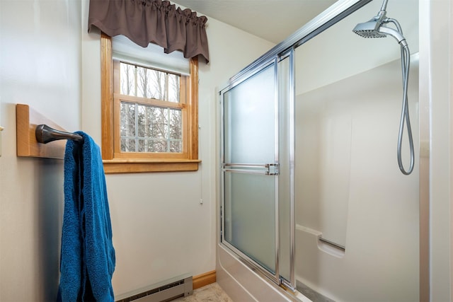 bathroom featuring baseboard heating and bath / shower combo with glass door