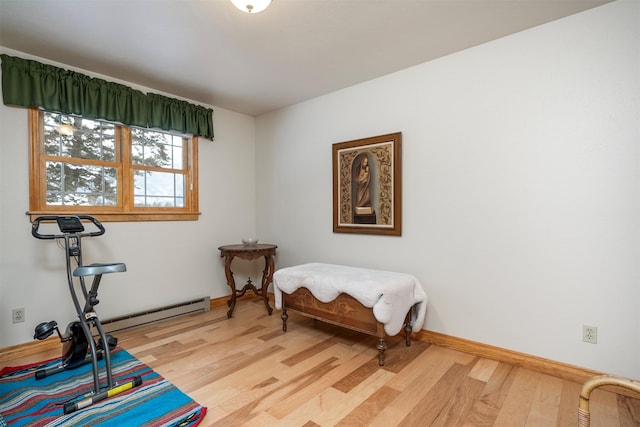 bedroom with a baseboard heating unit and light wood-type flooring