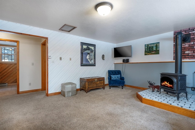 sitting room featuring carpet, a textured ceiling, and a wood stove