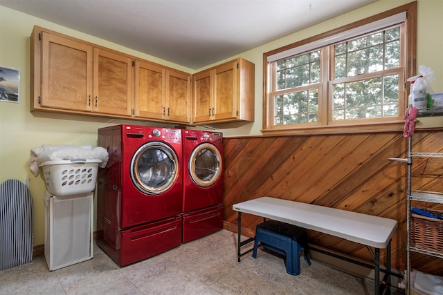 washroom with cabinets, washing machine and clothes dryer, and wood walls