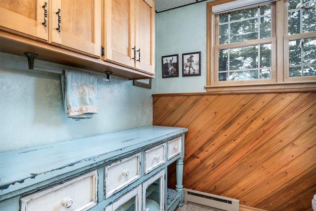 interior space with a baseboard heating unit and wooden walls