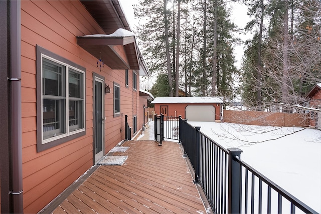 snow covered deck with a garage and an outdoor structure