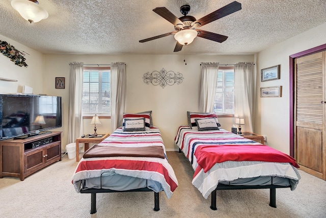 carpeted bedroom featuring multiple windows, a textured ceiling, and ceiling fan