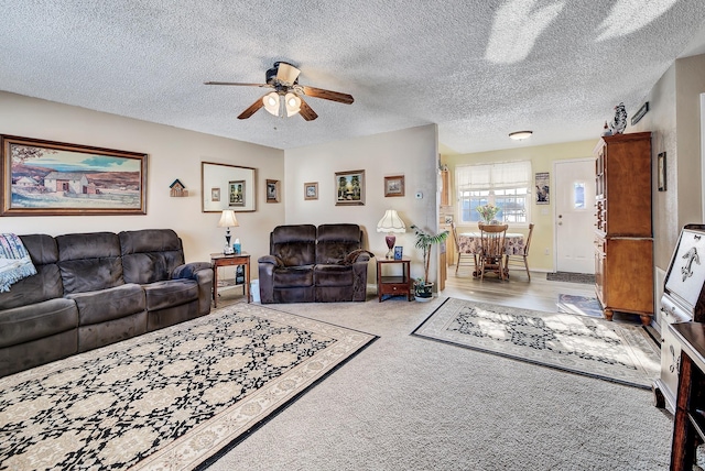 living room with a textured ceiling, light colored carpet, and ceiling fan