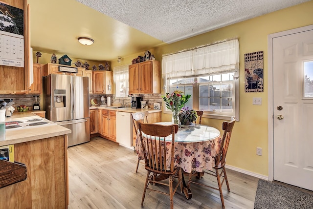 kitchen with tasteful backsplash, sink, white appliances, and light wood-type flooring