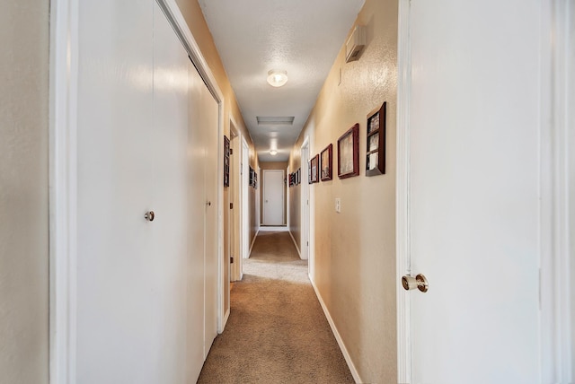 hall with light carpet and a textured ceiling