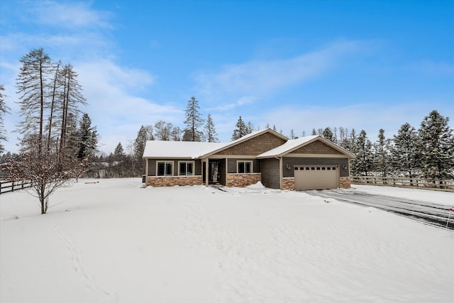 view of front of house featuring an attached garage, stone siding, and fence