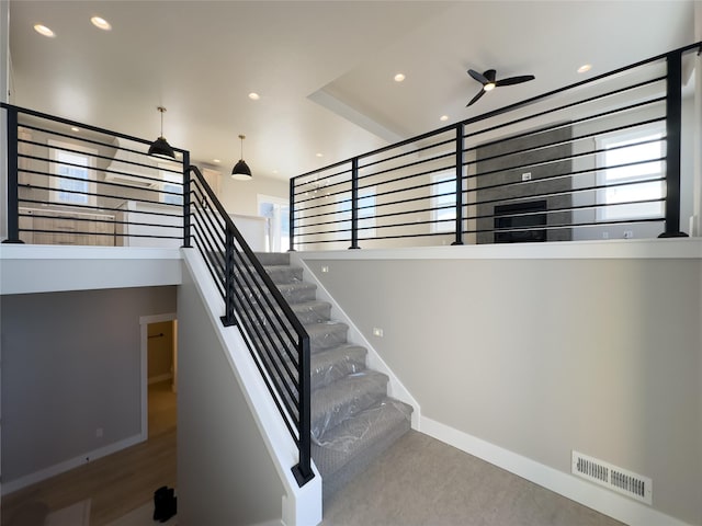 stairway featuring wood-type flooring and ceiling fan