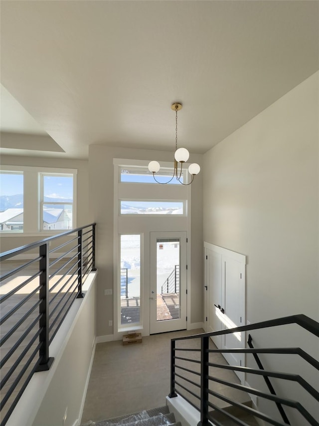 carpeted foyer entrance with a chandelier and a wealth of natural light