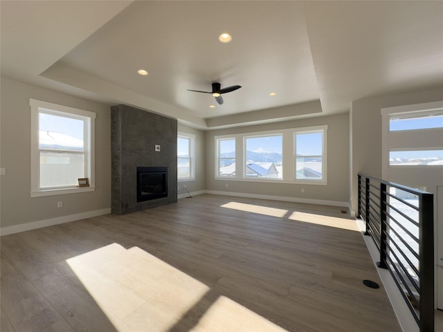 unfurnished living room with dark hardwood / wood-style flooring, a healthy amount of sunlight, a fireplace, and a raised ceiling