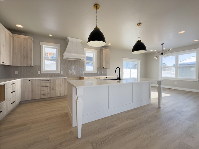 kitchen featuring sink, light brown cabinetry, an island with sink, and light hardwood / wood-style flooring