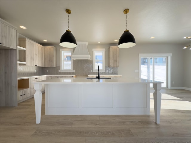 kitchen featuring pendant lighting, light brown cabinetry, sink, and custom exhaust hood