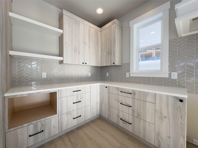 kitchen with light brown cabinetry, backsplash, and light hardwood / wood-style flooring