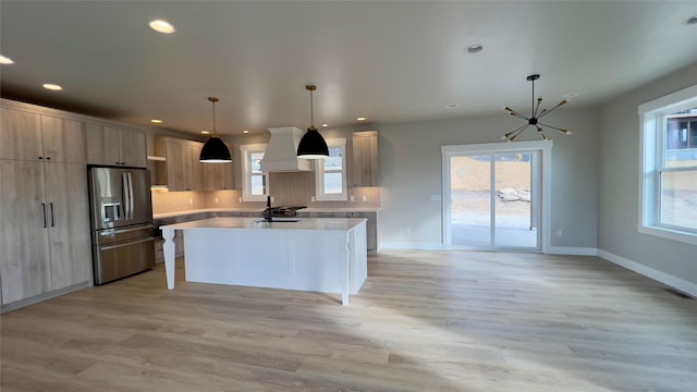 7018 Max Dr, Missoula, MT 59803 - kitchen featuring modern cabinets, light countertops, premium range hood, stainless steel refrigerator with ice dispenser, and a notable chandelier