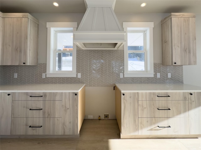 kitchen with decorative backsplash, light wood-type flooring, light brown cabinets, and premium range hood