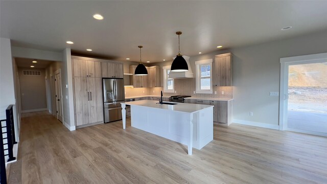 7018 Max Dr, Missoula, MT 59803 - kitchen featuring an island with sink, light countertops, a sink, light wood-style flooring, and appliances with stainless steel finishes