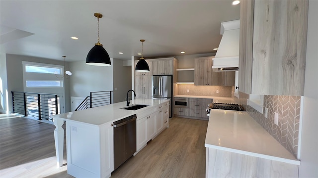 7018 Max Dr, Missoula, MT 59803 - kitchen featuring light wood finished floors, stainless steel appliances, a sink, backsplash, and premium range hood