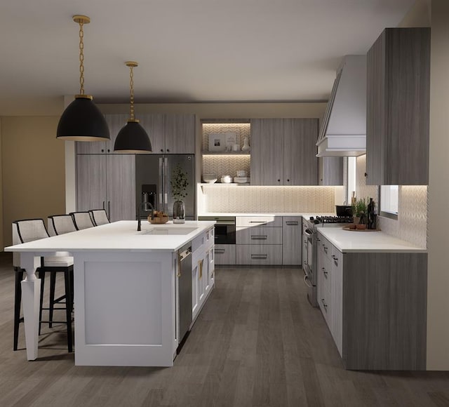 kitchen with pendant lighting, a breakfast bar, appliances with stainless steel finishes, custom range hood, and a center island with sink