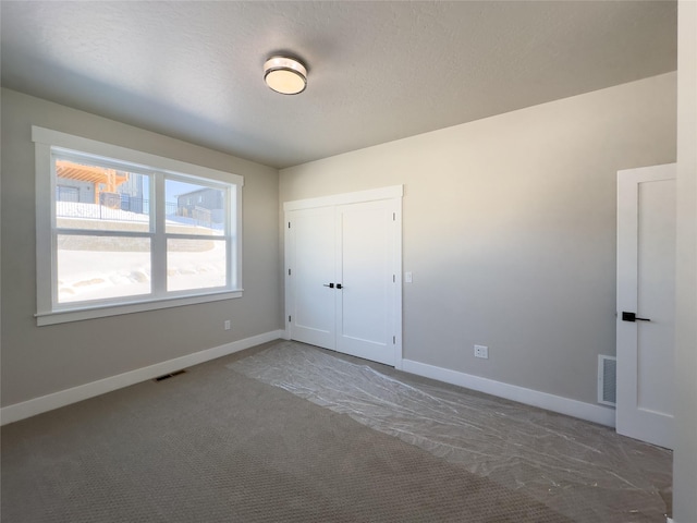 unfurnished bedroom with a closet, a textured ceiling, and carpet