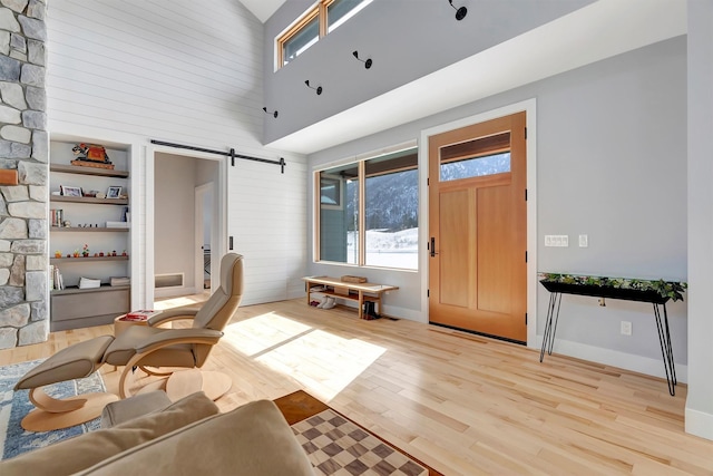 interior space with a towering ceiling, light hardwood / wood-style floors, and a barn door