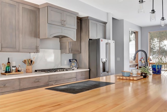 kitchen featuring stainless steel appliances, decorative light fixtures, butcher block counters, and gray cabinets