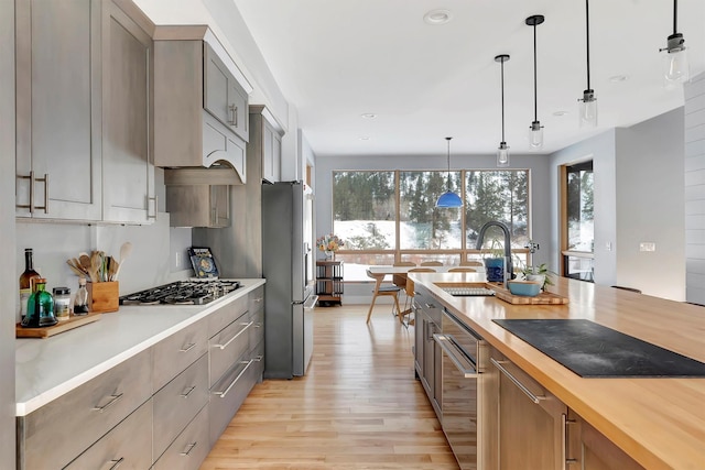 kitchen featuring stainless steel appliances, decorative light fixtures, sink, and butcher block countertops