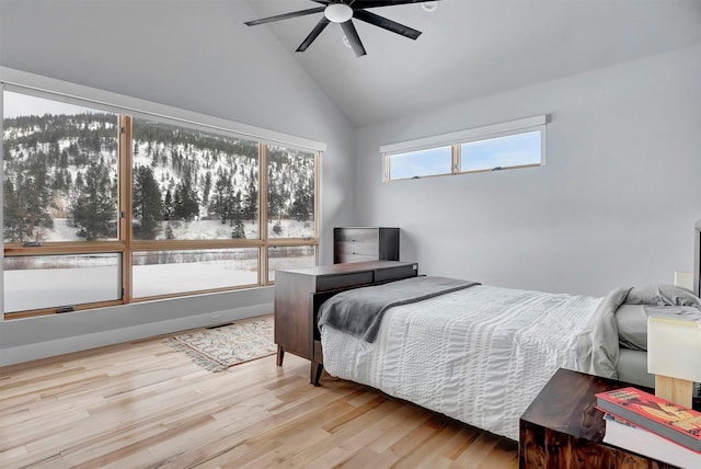 bedroom with ceiling fan, high vaulted ceiling, and light hardwood / wood-style floors