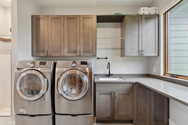 laundry room featuring cabinets, sink, a wealth of natural light, and washer and clothes dryer