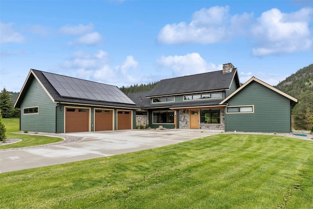 view of front of home featuring a garage, a front lawn, and solar panels