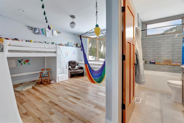 bedroom with multiple windows and light hardwood / wood-style flooring