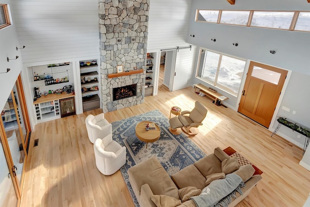 living room featuring a towering ceiling, a fireplace, a healthy amount of sunlight, and hardwood / wood-style flooring