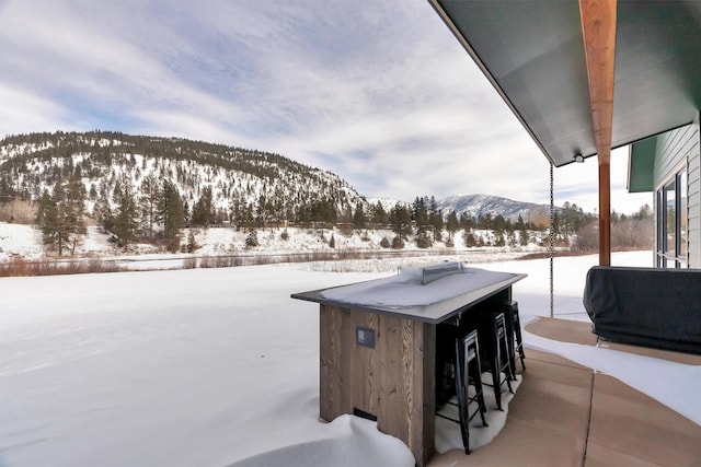 snow covered patio with a mountain view