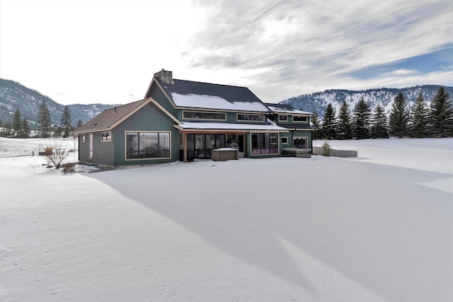 snow covered property with a mountain view and covered porch