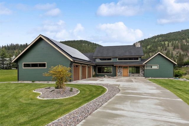 view of front of house featuring a garage, a mountain view, and a front lawn