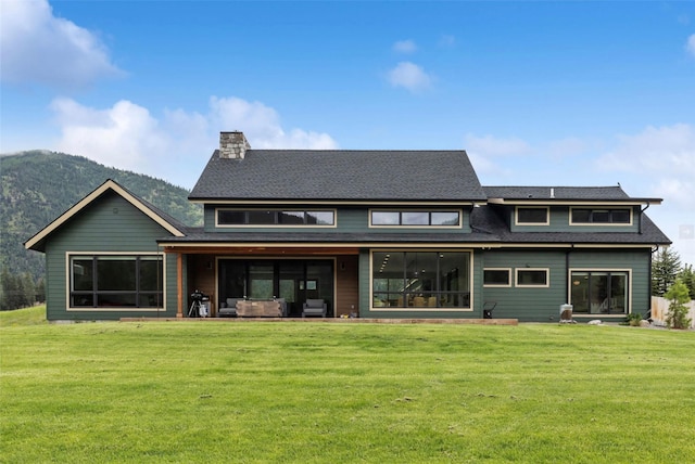 rear view of property with a mountain view and a yard