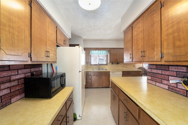 kitchen featuring white appliances, light countertops, a sink, and a textured ceiling