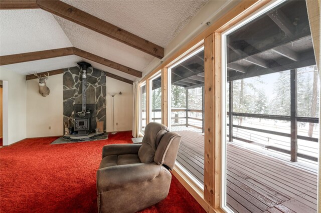 carpeted living area with lofted ceiling with beams, a wood stove, and a textured ceiling