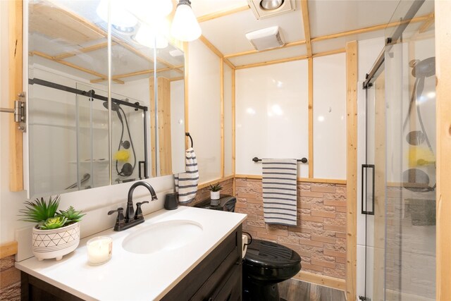 bathroom with toilet, wainscoting, a shower stall, vanity, and wood finished floors