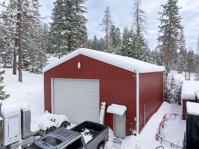 snow covered garage with a detached garage