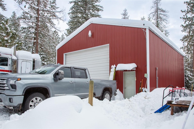 snow covered garage featuring a detached garage