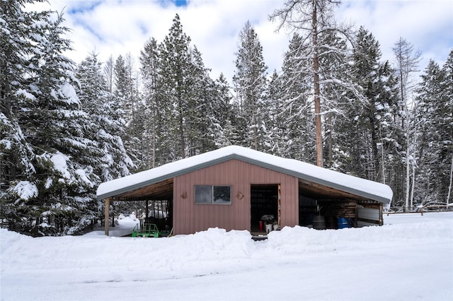 snow covered structure featuring a carport, a pole building, and an outdoor structure