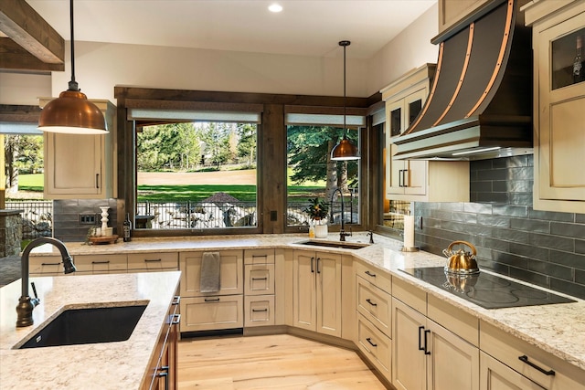 kitchen featuring hanging light fixtures, black electric stovetop, custom range hood, and sink