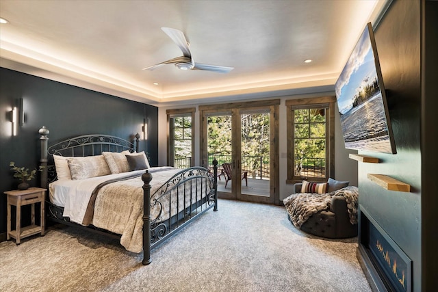 carpeted bedroom featuring french doors, ceiling fan, a tray ceiling, and access to outside