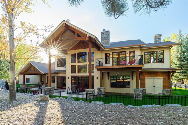 113 Levi Ct, Bigfork, MT 59911 - rear view of house with a balcony, a chimney, stone siding, roof with shingles, and a patio area