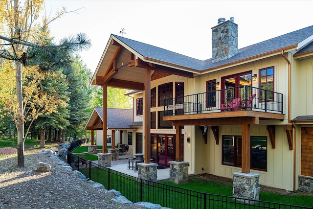 113 Levi Ct, Bigfork, MT 59911 - rear view of property featuring a fenced front yard, a balcony, a patio area, a chimney, and a shingled roof