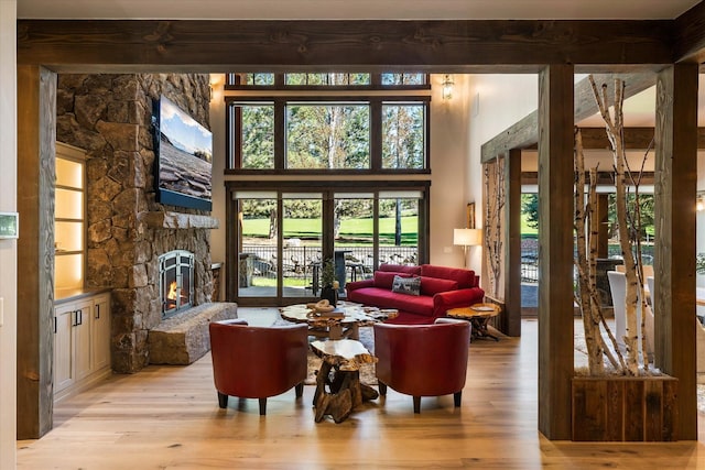 interior space with a stone fireplace, a towering ceiling, and light hardwood / wood-style floors