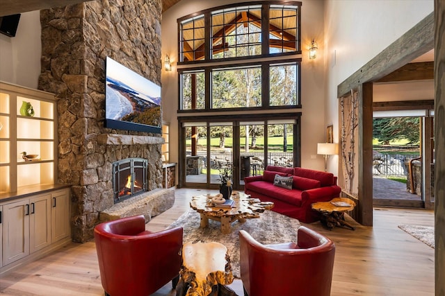 living room featuring a stone fireplace, plenty of natural light, and light hardwood / wood-style floors