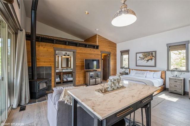 76 Rusty Iron Way, Eureka, MT 59917 - bedroom with wooden walls, vaulted ceiling, light wood finished floors, and a wood stove