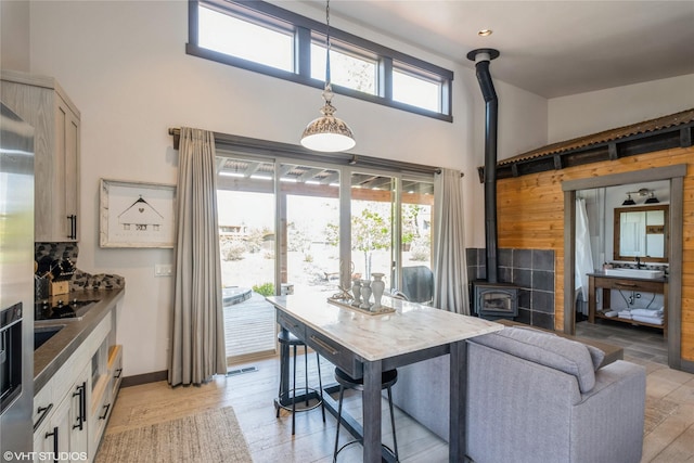 76 Rusty Iron Way, Eureka, MT 59917 - kitchen featuring a wood stove, a towering ceiling, stainless steel refrigerator with ice dispenser, tasteful backsplash, and wood walls